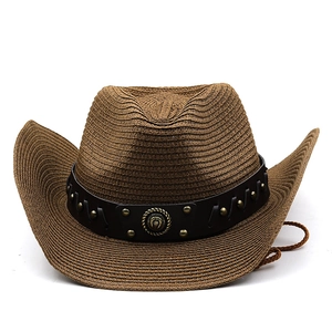 Detail of woven straw cowboy hat with leather rivet band and vintage metal emblem decoration