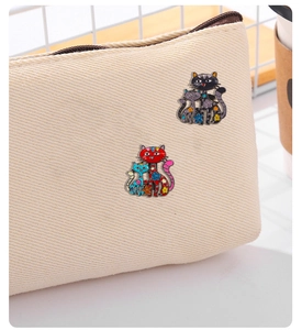 Détail de pins chat en émail coloré avec motifs floraux sur une surface en toile