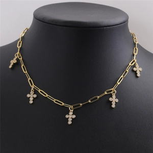 Détail d'un collier doré avec cinq petites croix en zircone sur un buste de mannequin noir