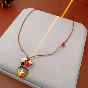 Close-up of bohemian heart pendant necklace with multi-colored wooden beads and wax cord