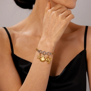Detail of beach style gold starfish shell and crab charms on a mixed metal link bracelet