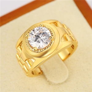 Gros plan d'une bague dorée pour homme avec un grand zircon et un anneau texturé gravé