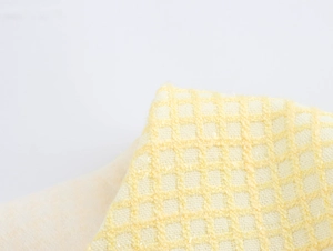 Close-up of pale yellow tweed fabric texture with classic waffle weave detail