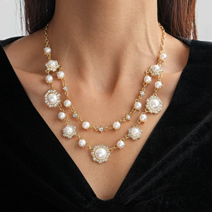 Detail van dubbellaagse ketting met zirkoon bladeren en parels op gouden ketting