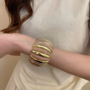 Detailed close-up of a wide acrylic resin and gold metal elastic cuff bracelet on a wrist