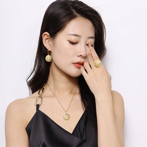 Close-up of model wearing gold spiral texture jewelry set with pearls on white background