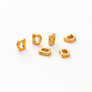 Detailed view of six gold-plated metal D-shaped letter beads with holes for DIY jewelry