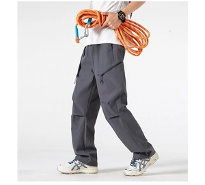 Detail of dark grey cargo pants featuring functional side zip pockets and loose fit cut