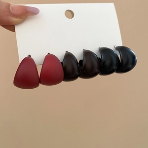 Detailed view of matte acrylic C-shaped earrings in dark red, brown, and black