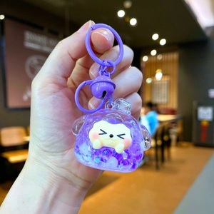 Detail of purple acrylic keychain with mini sheep figure, liquid glitter, and bell