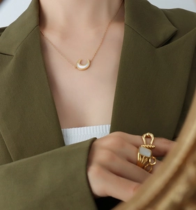 Detail of 18K gold plated moon pendant necklace with white sea shell on a model neck