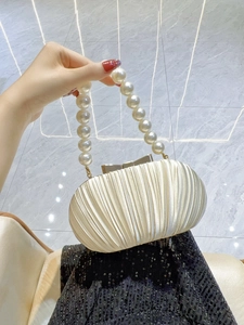Detail einer eleganten plissierten Satin-Abendtasche mit Perlenkordel und Metallverschluss