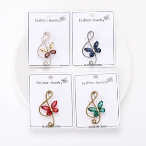 Detailed close-up of four rhinestone G-clef butterfly brooches in various colors