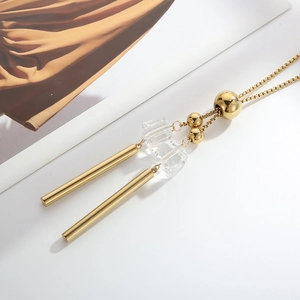 Detail of long sweater necklace with gold cylindrical pendants and clear faceted beads
