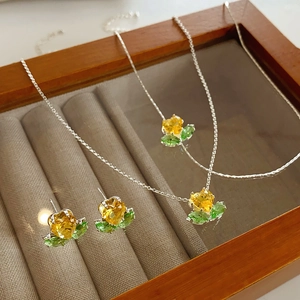 Detail von silbernen Blumenketten und Ohrringen mit gelben und grünen Zirkonsteinen