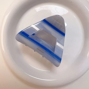 Dettaglio della pinza per capelli in acetato a righe bianche e blu con testo dorato