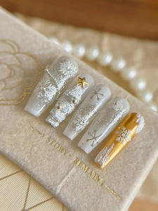 Close-up of 3D embossed Christmas snowflake nail tips with pearls and gold stars