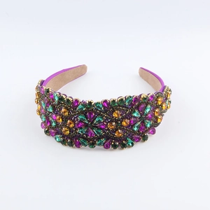 Macro detail of Baroque headband with purple and green crystals on white background