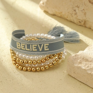 Set de 4 pulseras boho con cinta azul bordada y cuentas doradas sobre arena