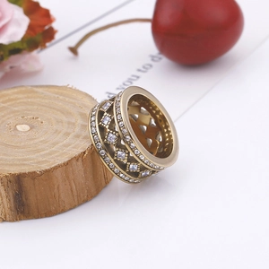 Detailansicht eines breiten goldenen Netzrings mit weißen Zirkonia auf Holzständer