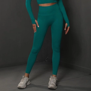 Detail of teal high-waisted seamless yoga leggings and long sleeve top with thumb holes