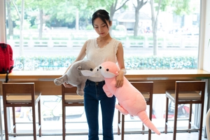Detail showing two plush otter toys in grey and pink being held by a person in a cafe