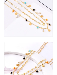 Macro detail of multi-layered gold titanium necklace with star charms and colorful beads