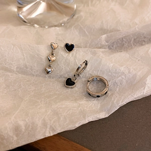 Detailed view of silver and black enamel heart earrings and ring set on textured paper