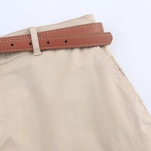 Detail view of khaki casual shorts featuring a brown faux leather belt and fabric texture