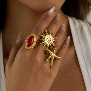 Detail of red agate and gold sun starfish rings set worn on a model's hand