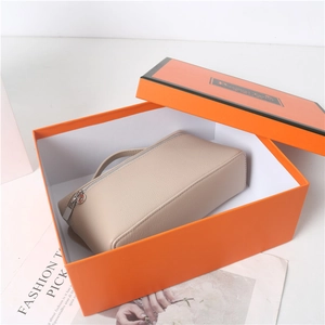 Detailed view of beige pebble grain leather handbag in a premium orange gift box