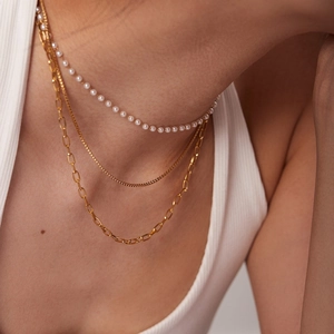 Classic French gold layered necklace with white pearls on a model in soft lighting