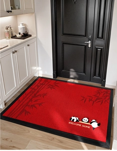 Detail der roten Fußmatte mit Pandamuster und Welcome Home Text auf Holzboden