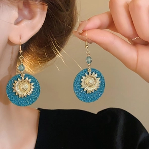 Detail showing vintage sunflower earrings with teal resin and golden metal accents