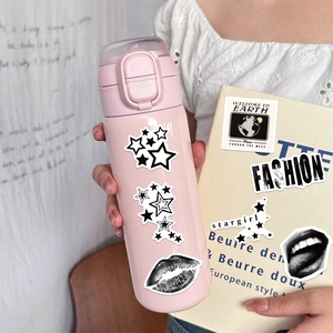 Close-up of Y2K waterproof black and white stickers on a pink tumbler and cream book