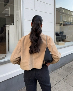 Vue arrière d'une veste courte en daim kaki avec jean noir et sac à bandoulière chic