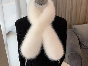 Detailed view of white faux fox fur scarf with cross-over styling on black sweater