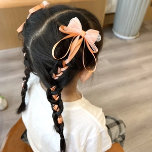 Detail of girl's hair braided with orange mesh bow clips and long ribbon hairpins