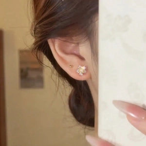 Close-up of elegant flower stud earrings with yellow and white zircons on a model