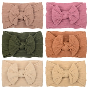 Detail view of 6 colorful knitted nylon baby headbands with soft texture and bows