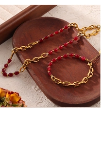 Detail view of 18k gold plated chain with red teardrop stones on dark wood tray