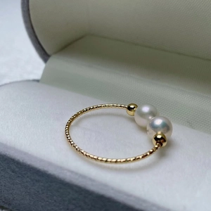 Detail of elegant gold spiral ring with dual pearls in a gray velvet jewelry gift box
