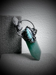 Detail of green hexagonal crystal pendant with vintage silver leaf and claw design