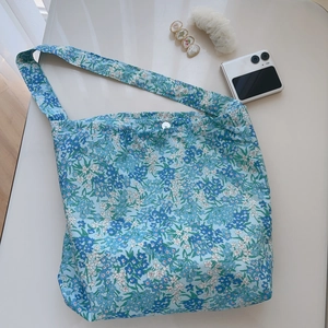 Detail of floral cotton shoulder bag featuring blue flower prints and button closure
