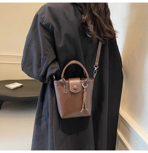 Lifestyle view of a vintage brown bucket bag worn by a model in a black coat