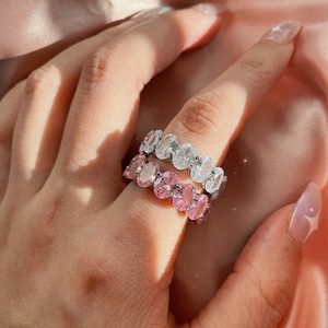 Close-up of stacked S925 silver rings with pink and white oval zircons on pink silk