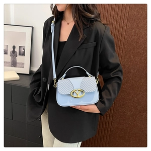 Detail of blue crossbody bag with herringbone flap and golden Y-shaped metal clasp