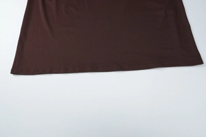Gros plan détaillé de l'ourlet de la robe marron foncé montrant le tissu et la couture