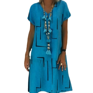 Detail of blue V-neck dress with black geometric lines and a long tassel necklace accessory