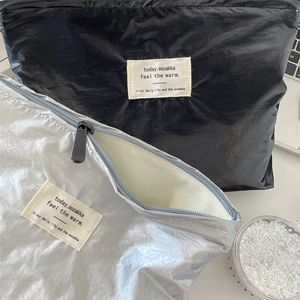 Detail view of silver shiny makeup bag showing the smooth zipper and inner canvas lining